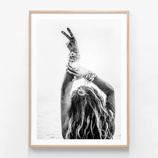 This image features a striking black and white photograph titled "Deuces," showcasing a close-up view of a person’s hand making a peace sign. The framed art print is artistic and evocative, with a high contrast that highlights the contours and texture of the hand and fingers against a softer background.