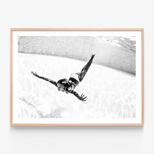 Framed artwork print of a girl swimming underwater in a pool. Black and white photography.