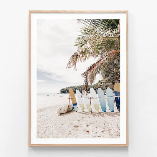 A framed photo wall art print featuring surfboard on the beach of a tropical coastline