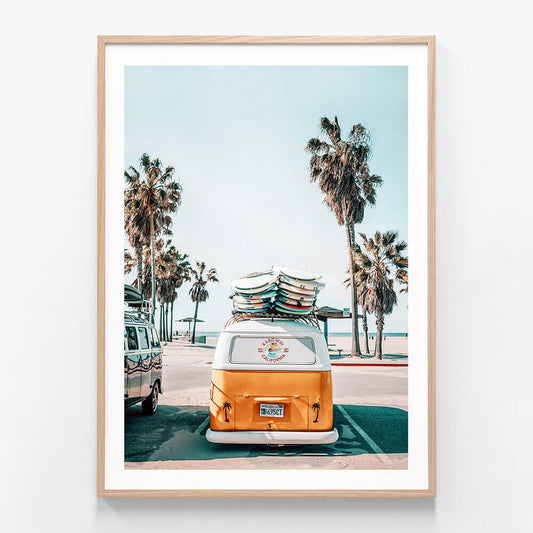 A framed photo wall art print featuring a surf van with surfboards by the beach