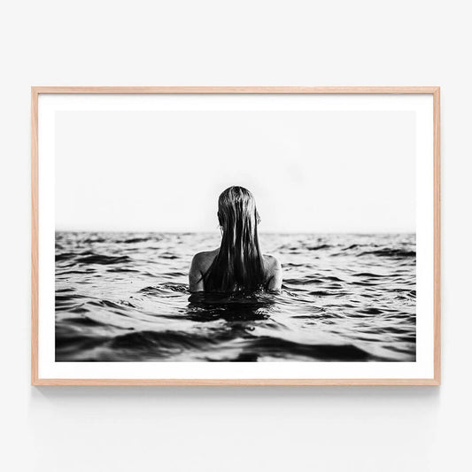 A black and white framed print of a person swimming in open water, viewed from behind, with only their head and part of their body visible above the water surface.
