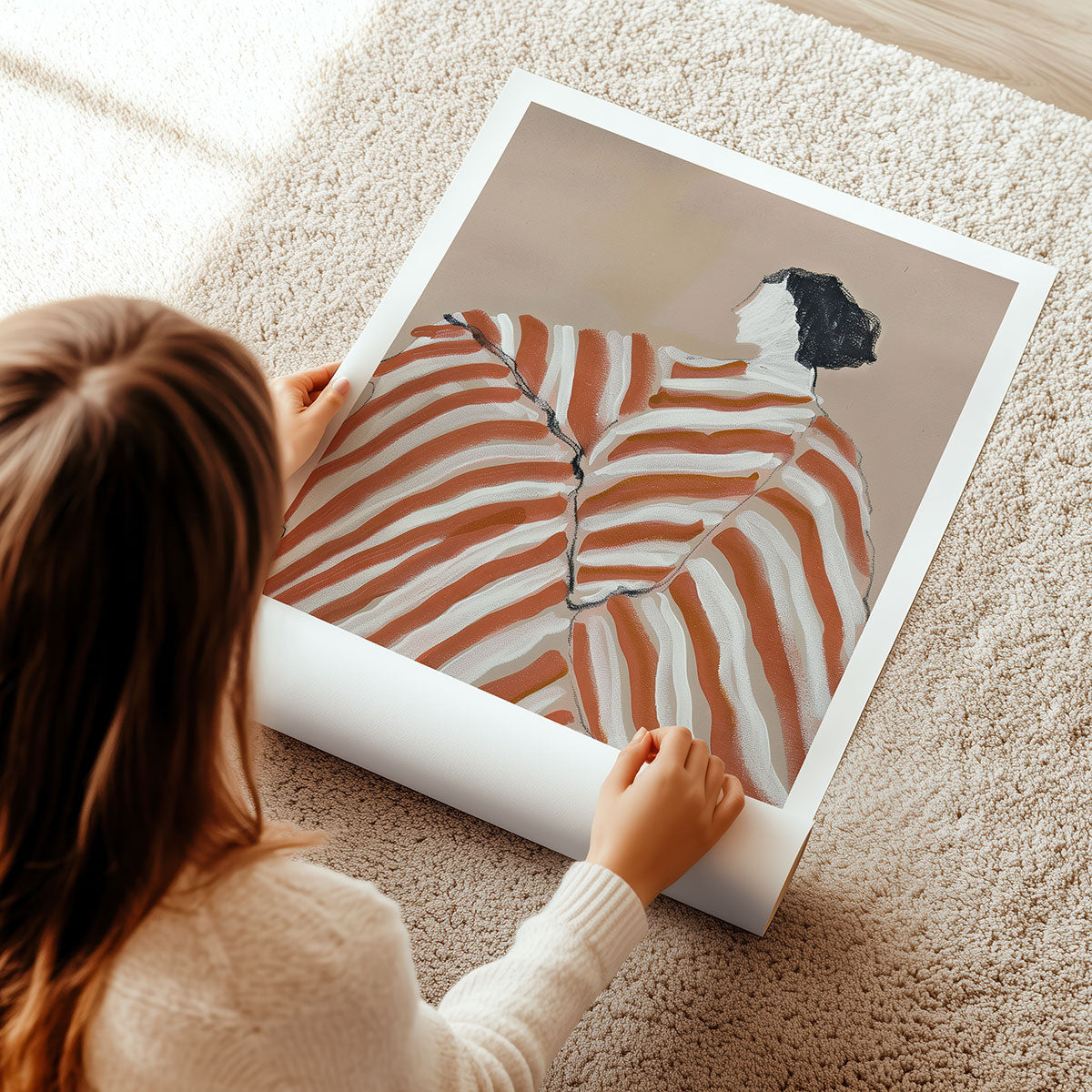 Person unrolling a large artwork print of a person in a striped outfit on a carpeted floor.