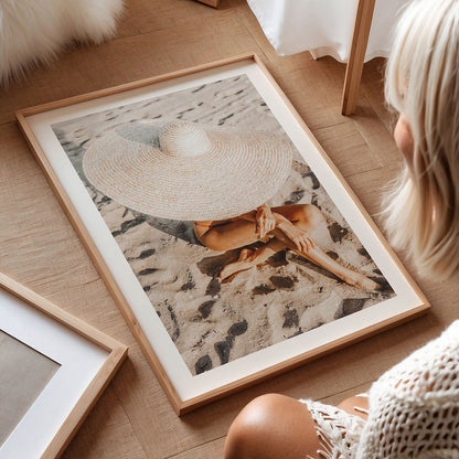 Framed photography wall art print of a person on the beach wearing a straw hat to showcase a luxury lifestyle.