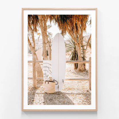 A framed photo wall art print featuring a surfboard and a coastal setting