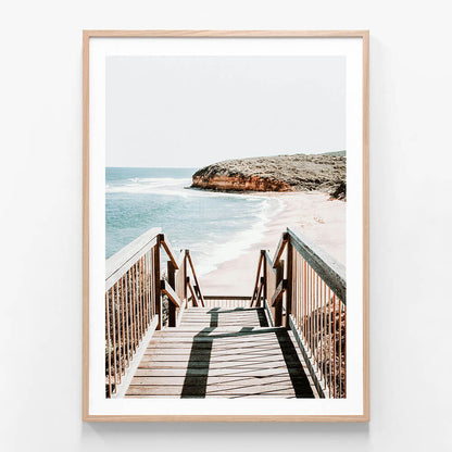 A framed photo print of a staircase leading down to Bells beach with the ocean and a headland in the background.