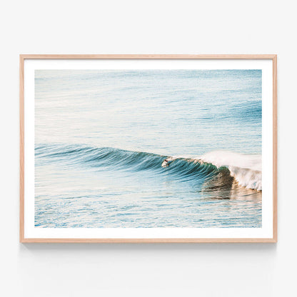 A photographic print featuring a surfboard on a gentle wave in the ocean at Bells beach, with a minimalist style and a blue and white color palette.