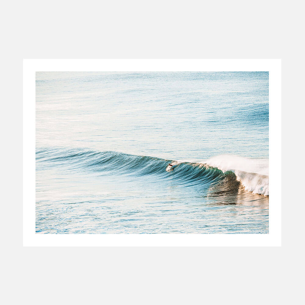 A photographic print featuring a surfboard on a gentle wave in the ocean at Bells beach, with a minimalist style and a blue and white color palette.