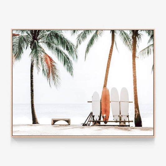 Surfboards on a rack under palm trees on a tropical beach photo canvas wall art with oak float frame