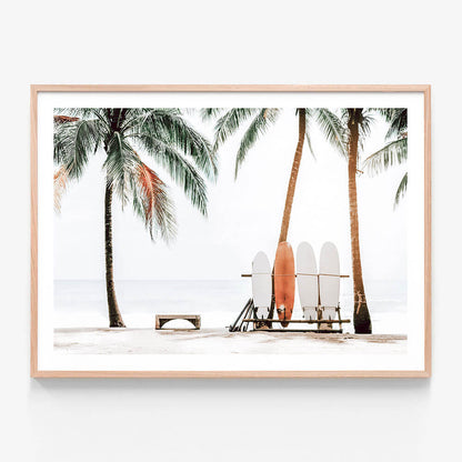 A framed photo wall art print featuring surfboards leaning against a beach chair with palm trees in the background.