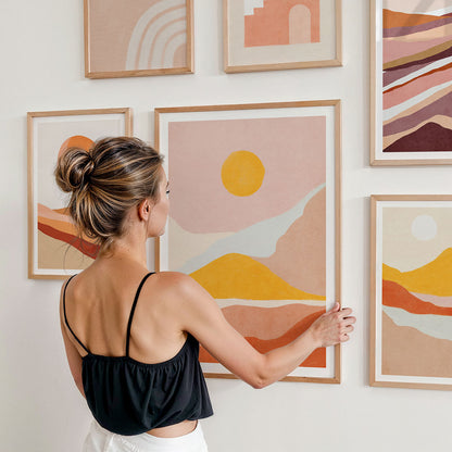 Woman arranging boho style art prints on a gallery wall
