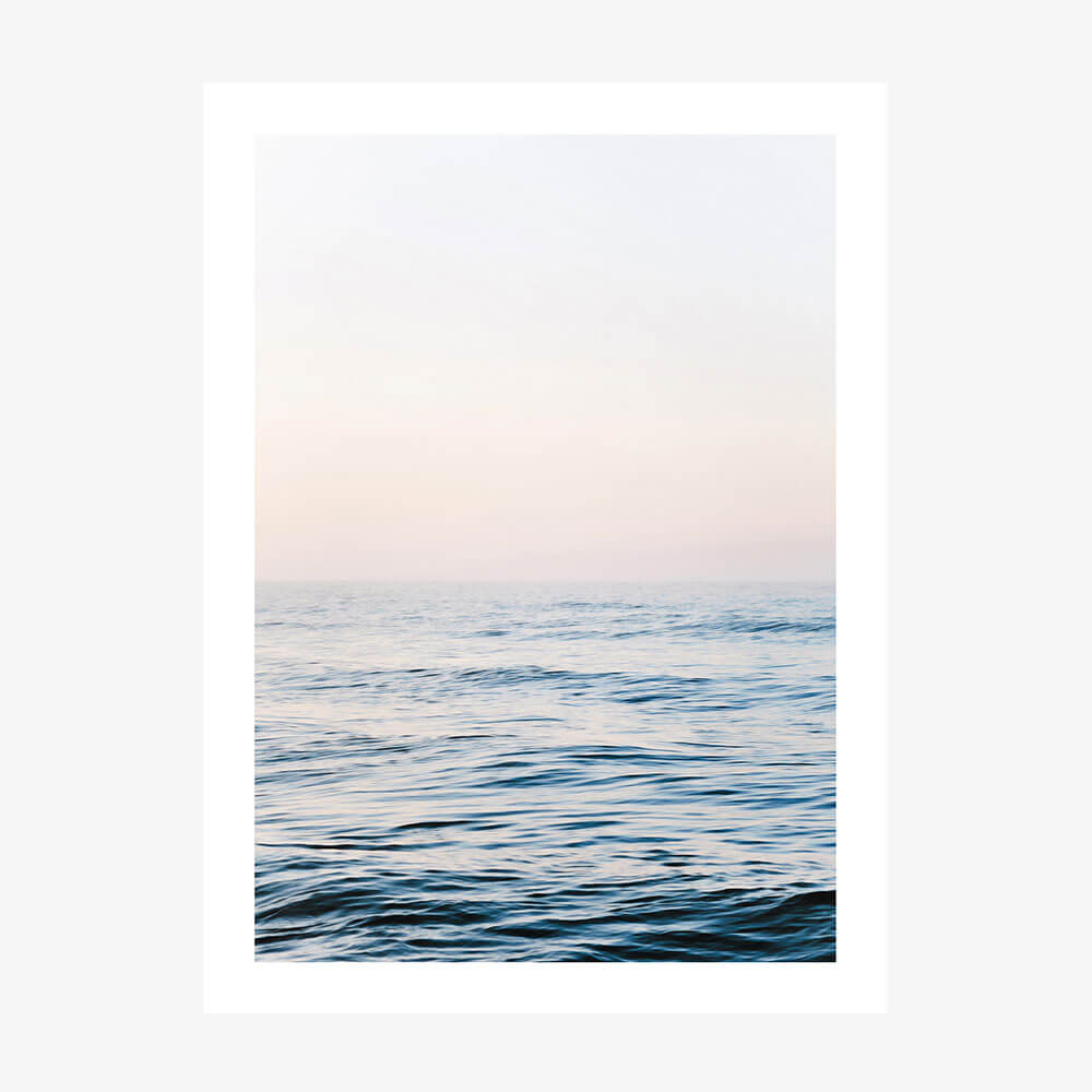 A framed picture of a calm ocean with a minimalist design, featuring gentle waves and a soft blue color palette.