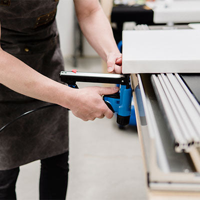 A close up of a canvas print being assembled and stapled to the frame.