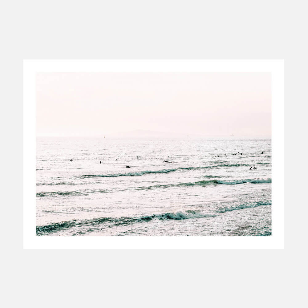 A poster print with a coastal surfboard theme, featuring a body of water with gentle waves and individuals on surfboards.