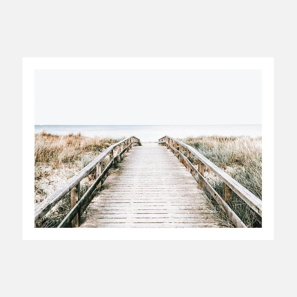 A print of a coastal boardwalk leading towards the ocean, with a bright sky and grassy dunes on either side.