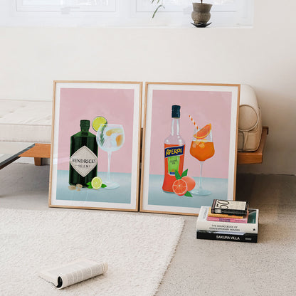 Two framed Wall art prints of cocktail posters on a wall with books below.