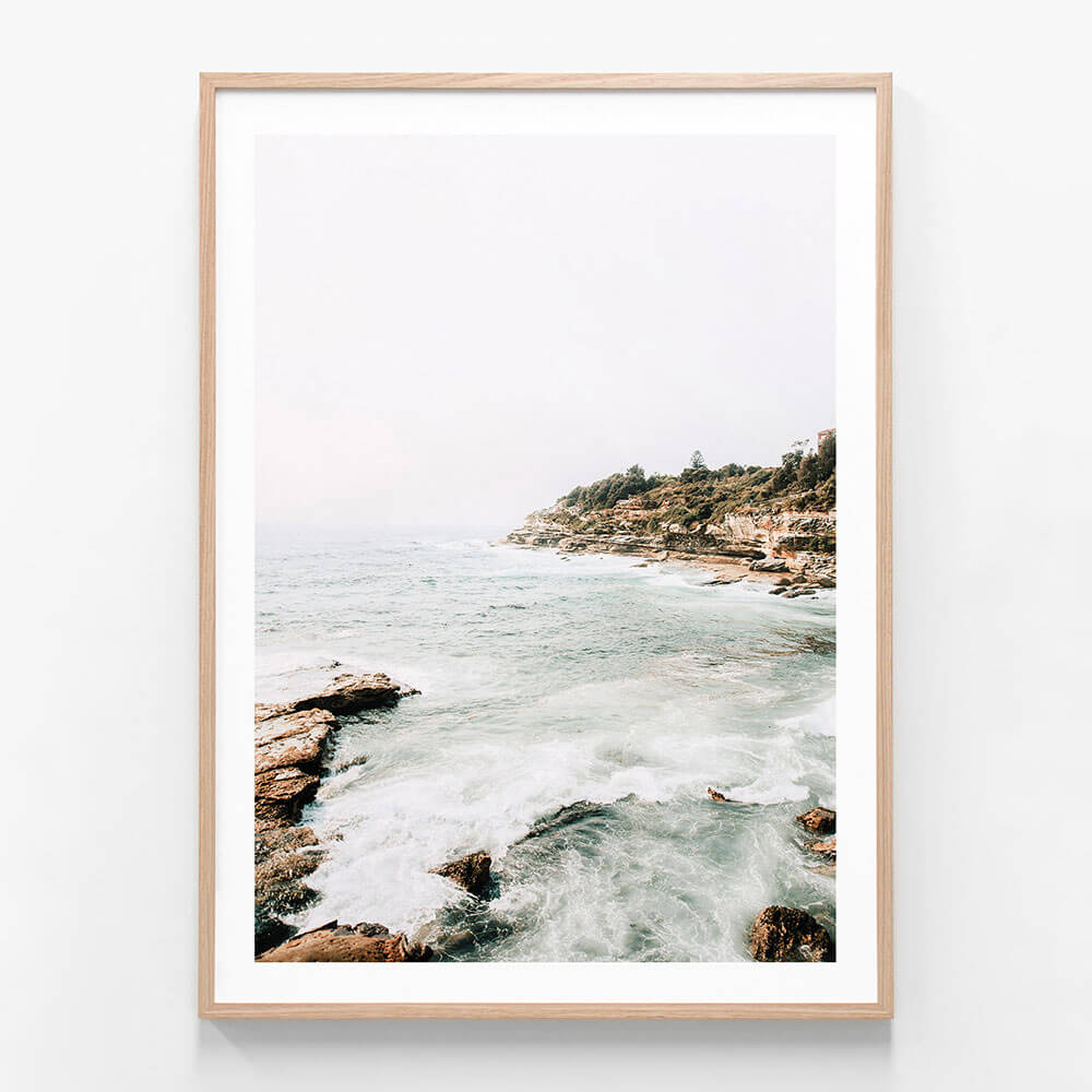 A framed photo print featuring the Coogee Coast with ocean waves and a rocky shore, providing a serene view of nature.