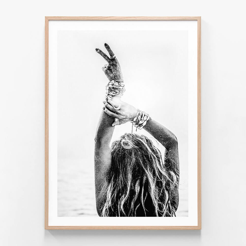 This image features a striking black and white photograph titled "Deuces," showcasing a close-up view of a person’s hand making a peace sign. The framed art print is artistic and evocative, with a high contrast that highlights the contours and texture of the hand and fingers against a softer background.