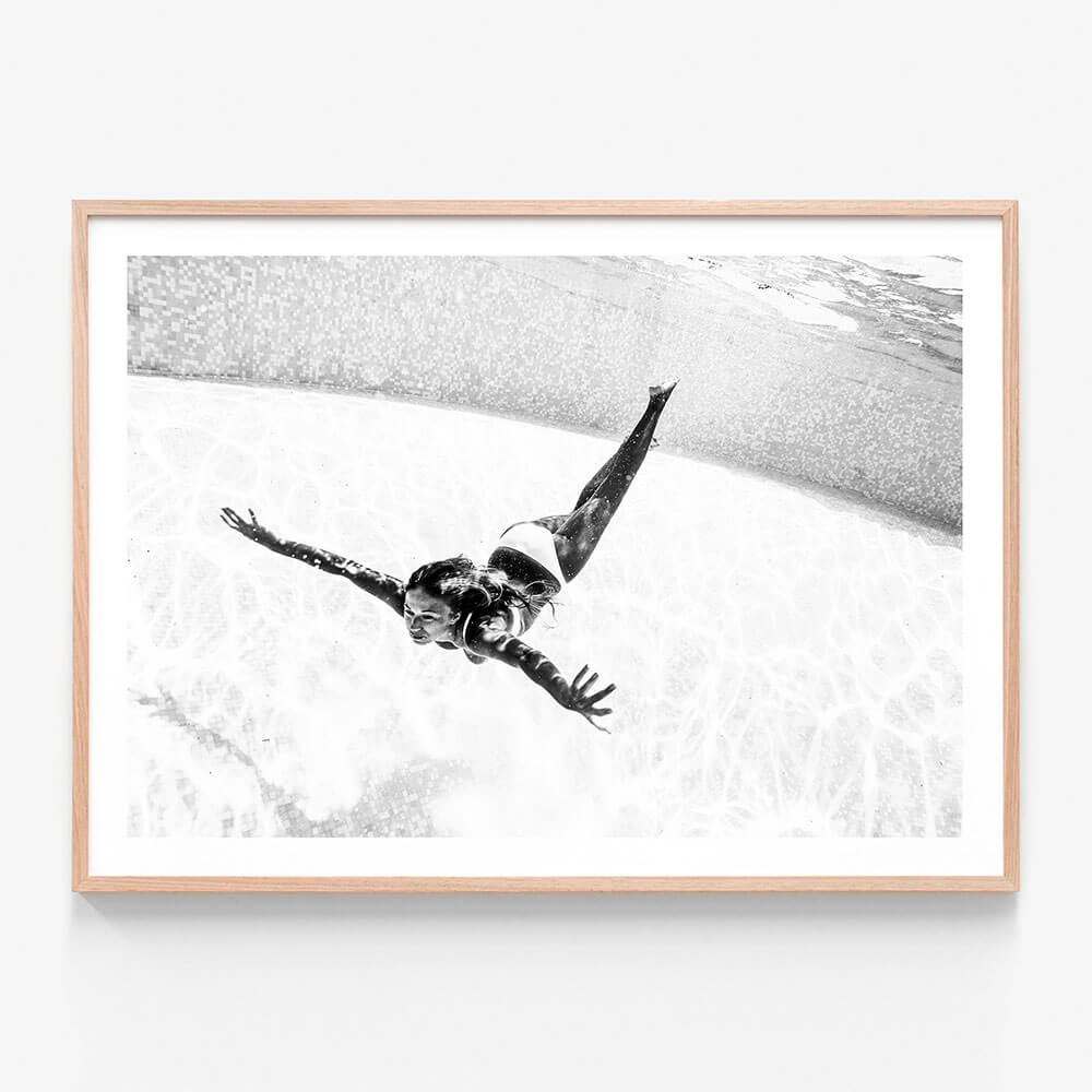 Framed artwork print of a girl swimming underwater in a pool. Black and white photography.