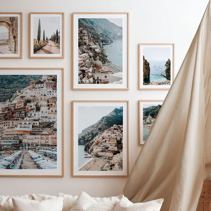 Framed photographic print of European coastal landscapes on a wall above a sofa in the style of a gallery.