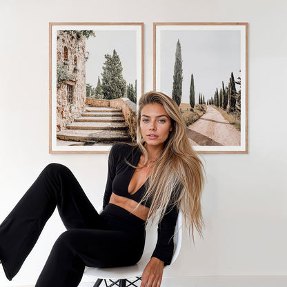 Woman sitting on a chair in a room with two framed photographic prints on the wall from Tuscany Italy.