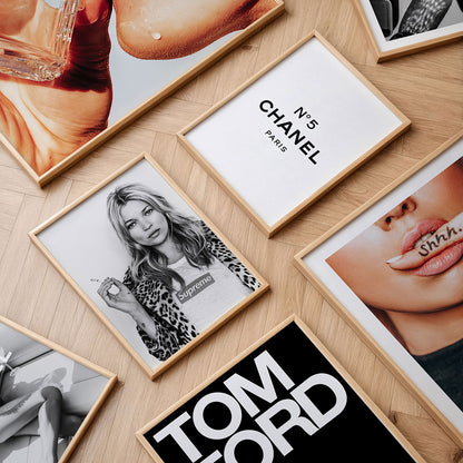 Collection of fashion wall art prints and framed posters on a wooden surface