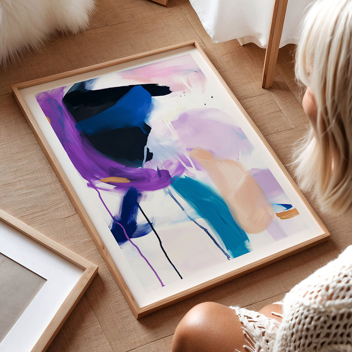 Person looking at a colourful framed artwork print on a wooden floor