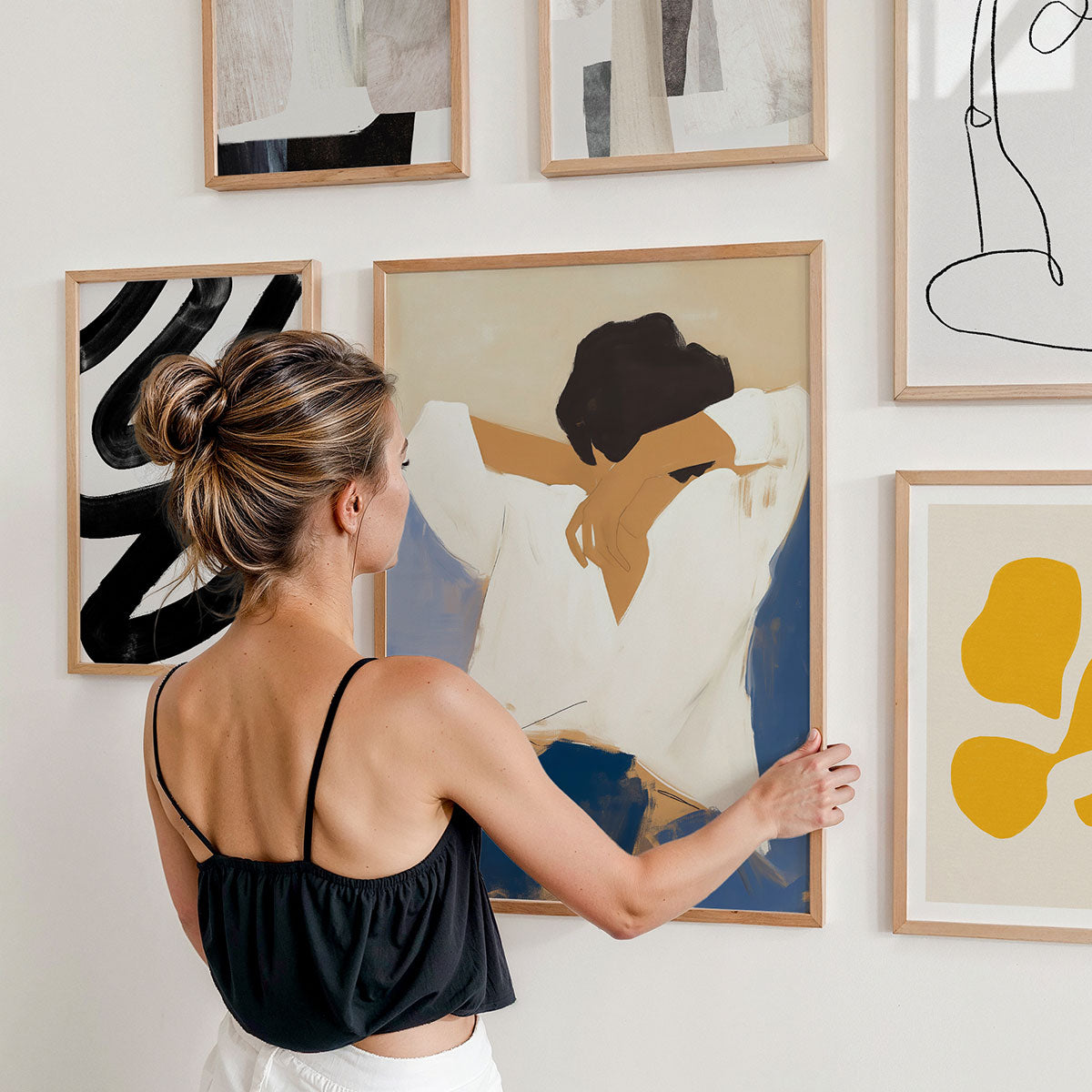 Woman arranging abstract art print on a gallery wall.