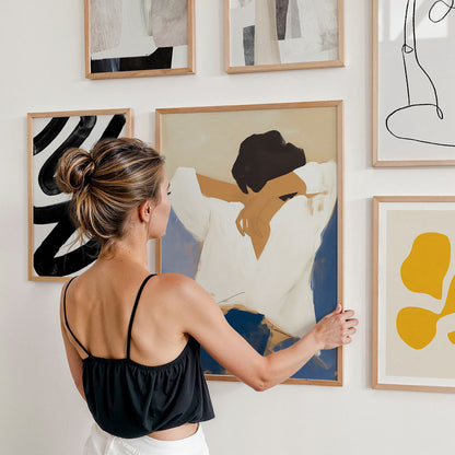 Woman arranging abstract art print on a gallery wall.
