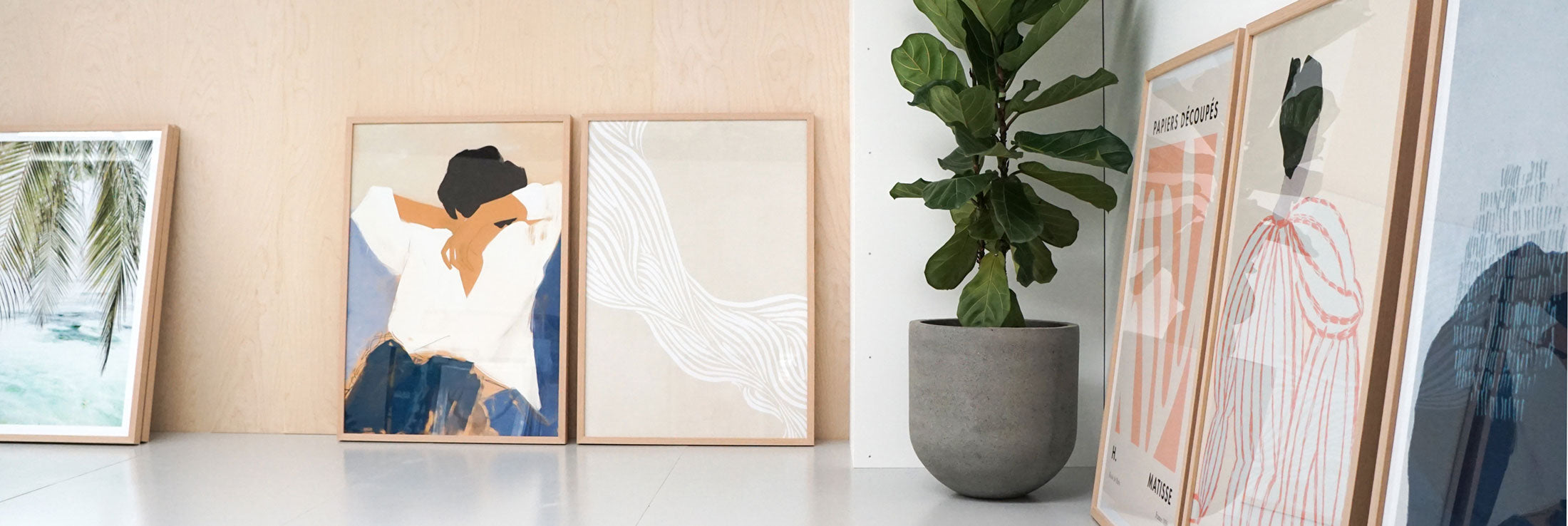 Framed wall art prints on a shelf with a potted plant in our Geelong showroom.