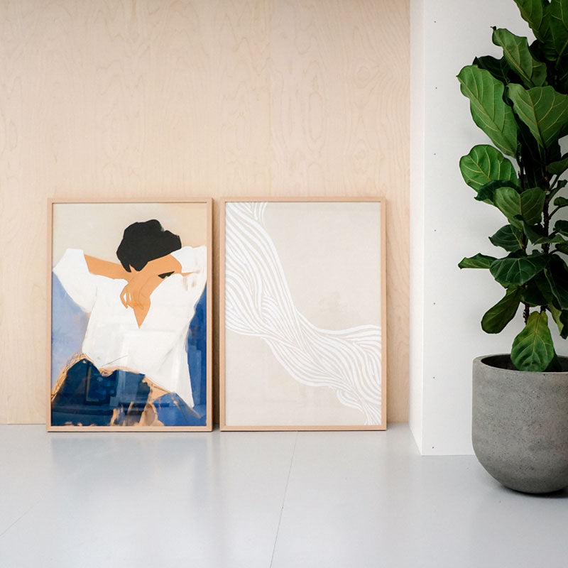 Two framed artworks on a shelf with a potted plant beside them in our Geelong Showroom.
