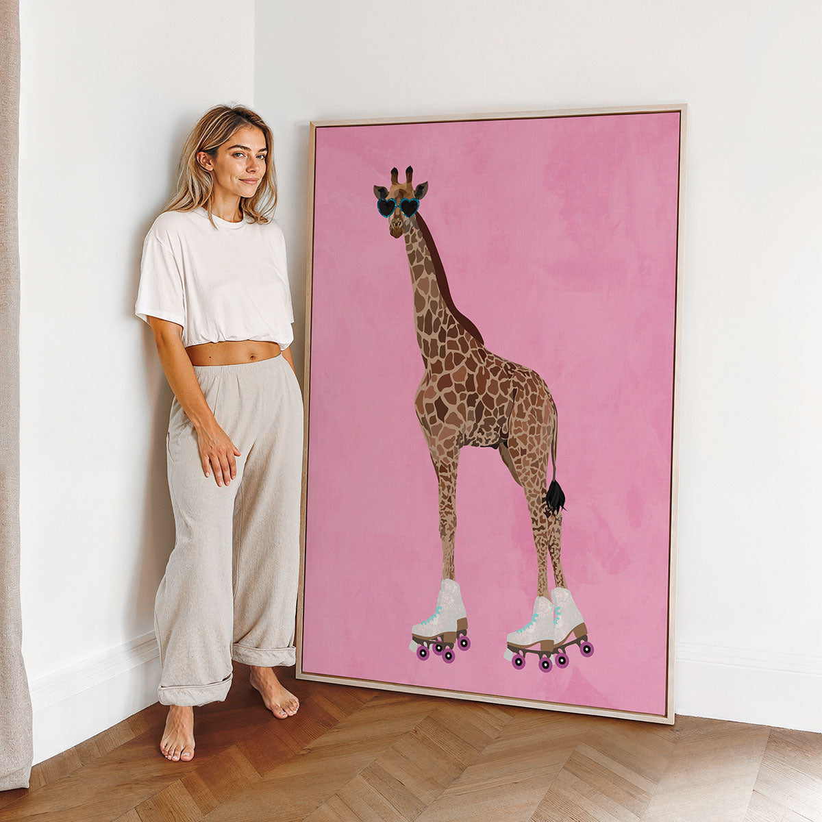 Woman in a kids room or nursery next to a framed canvas artwork of a giraffe on roller skates against a pink background