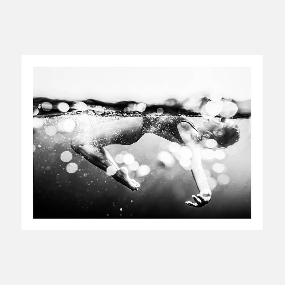 This framed print titled "Immerse" features a striking black and white photograph of a person swimming underwater. 