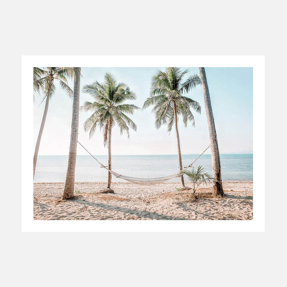A photo art print featuring a hammock strung between two palm trees on a beach, with the ocean in the background.