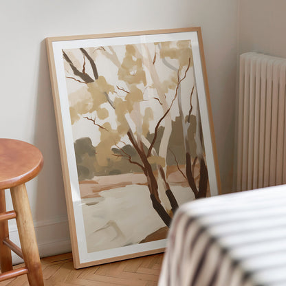 Framed artwork of trees leaning against a wall in a modern interior.
