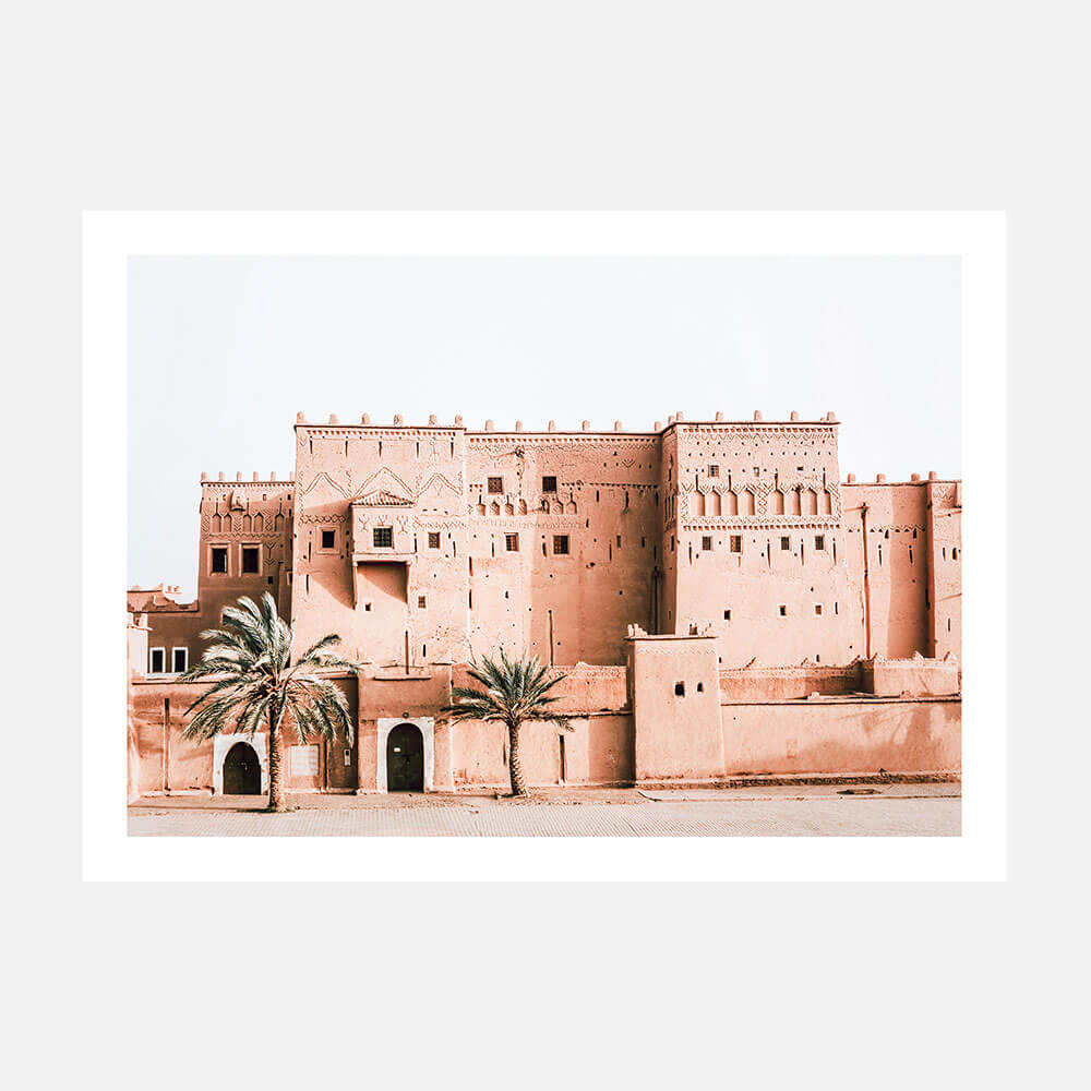 A photo art print of a Moroccan kasbah with adobe walls and several gates or openings, surrounded by palm trees.