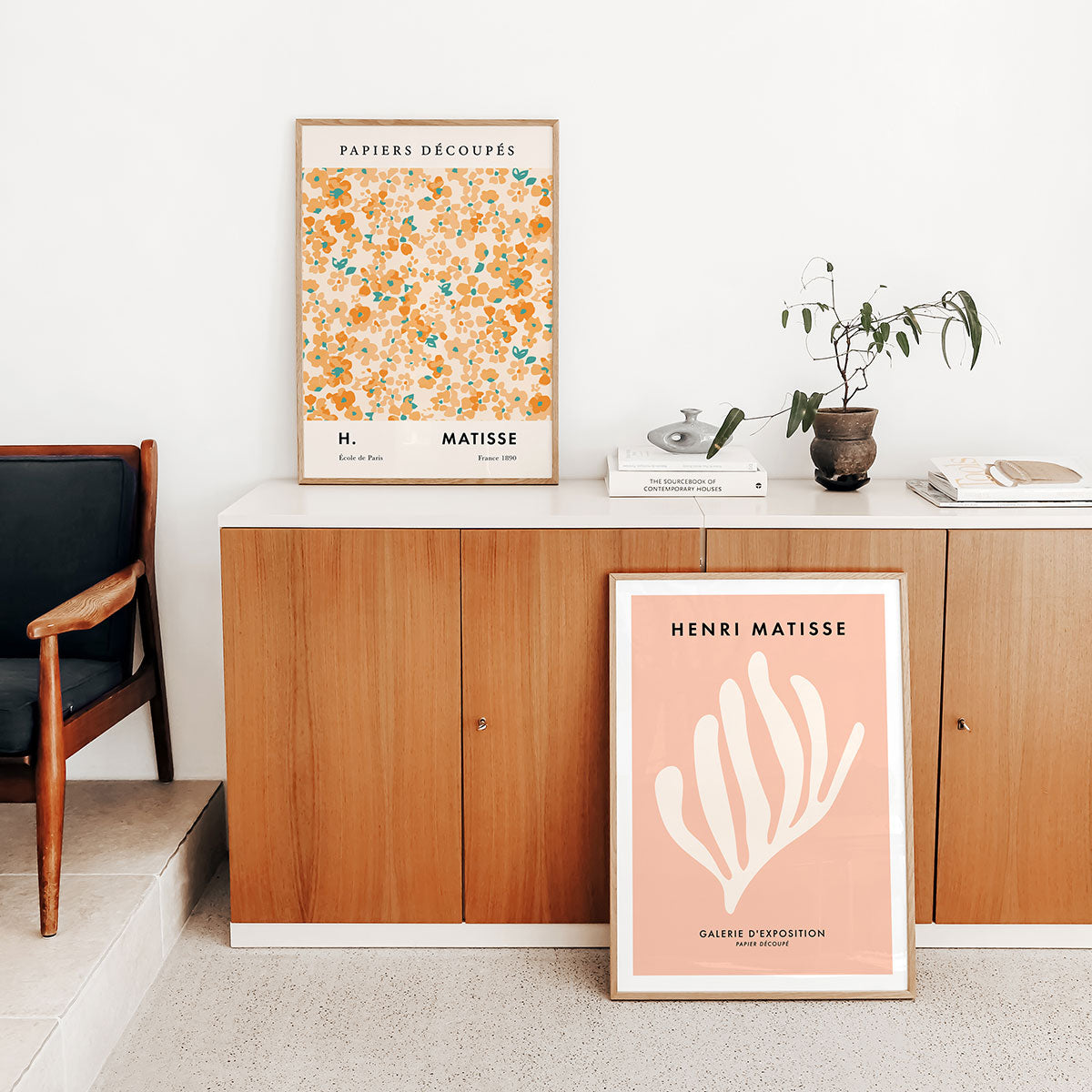 Framed Henri Matisse art prints on a shelf with a wooden cabinet and chair.
