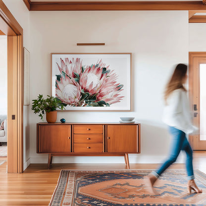 Living room with a wooden sideboard, floral artwork, and a person walking by.