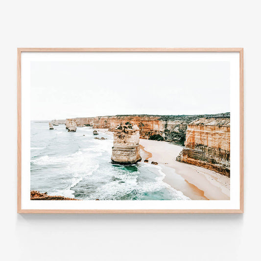 A framed printed artwork depicting a coastal scene with the cliffs and ocean at the 12 Apostles along the great ocean road