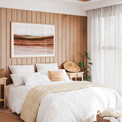 Neatly made bed with white bedding and beige blanket in a bedroom with a framed print of an abstract landscape painting having on the wall.