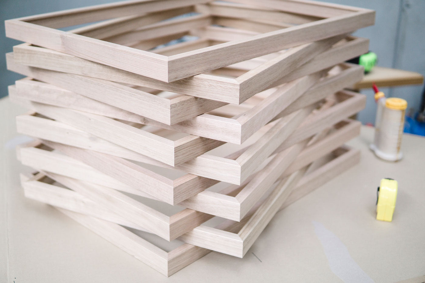 Stack of wooden picture frames on a table with tools in the background