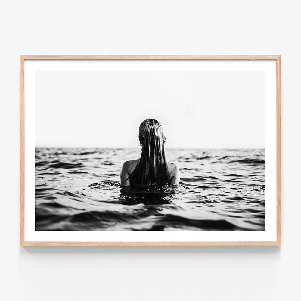 A black and white framed print of a person swimming in open water, viewed from behind, with only their head and part of their body visible above the water surface.