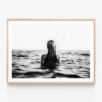 A black and white framed print of a person swimming in open water, viewed from behind, with only their head and part of their body visible above the water surface.