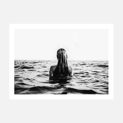 A black and white wall art print of a person swimming in open water, viewed from behind, with only their head and part of their body visible above the water surface.