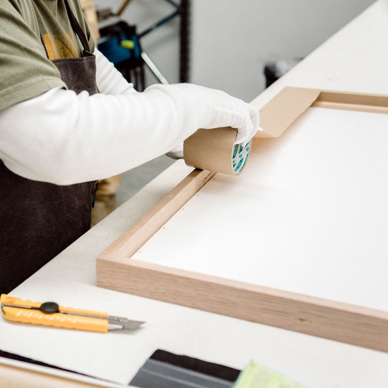 Steve working on a framed print, taping up the back and adding the hanging hardware.