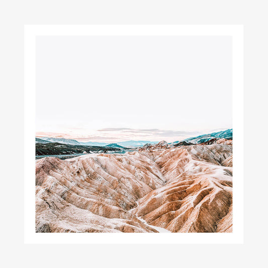 A landscape photo print of eroded badlands with hues of brown, beige, and blue, likely taken in a desert region.
