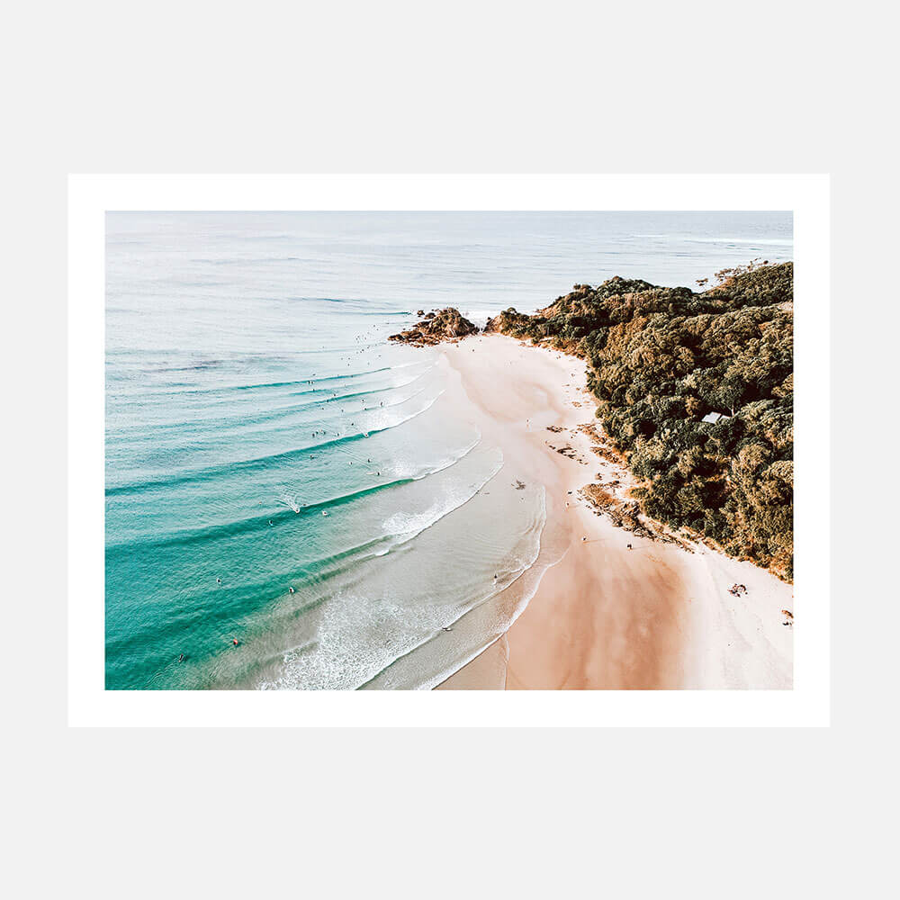 An overhead photo of the beach at the pass in Byron Bay with blue ocean waves and a rocky coast.