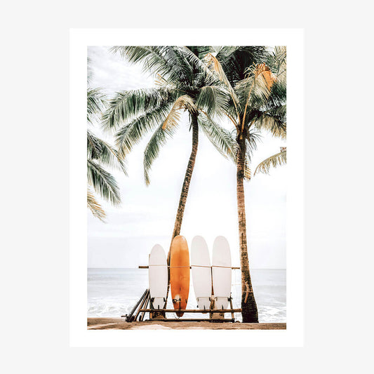 A wall art print featuring a tropical beach scene with palm trees, a bench, and multiple surfboards placed against a white backdrop.