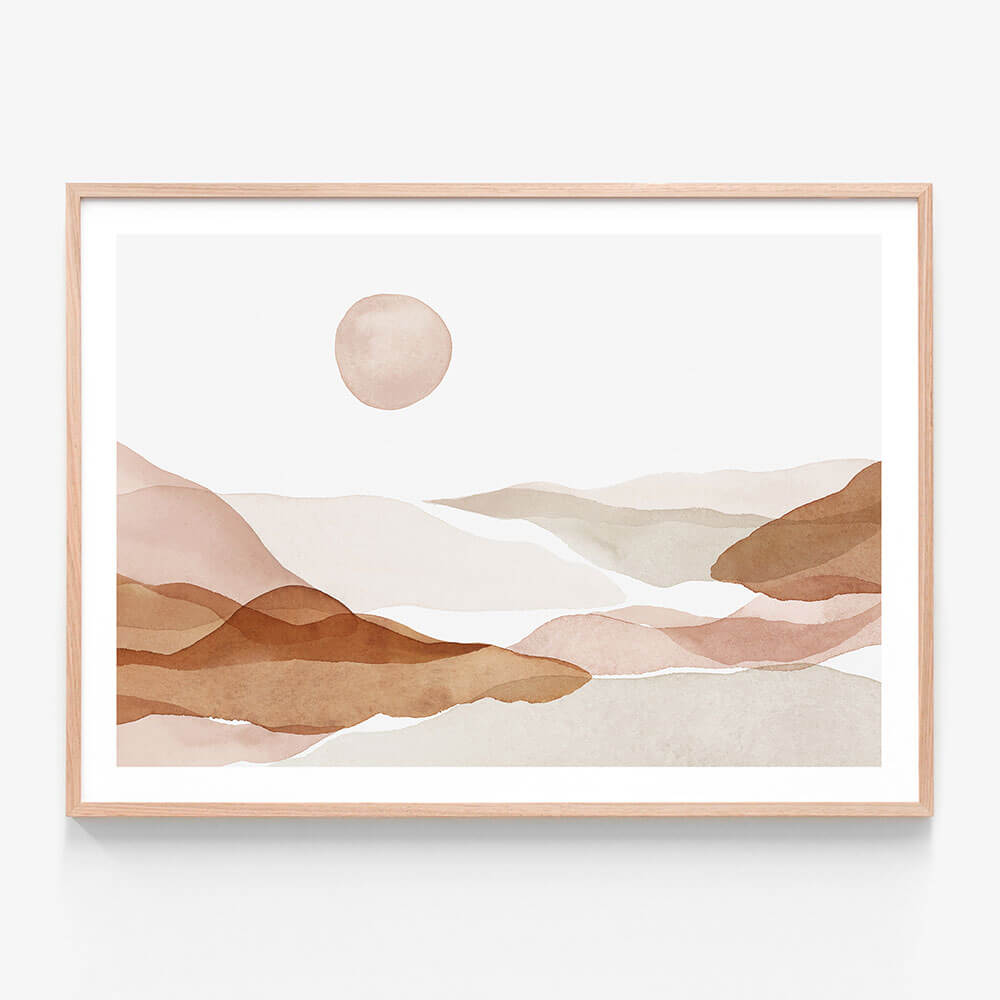 A framed art print of a watercolor painting of abstract hills in beige, brown, and white colors with a sun in the background.