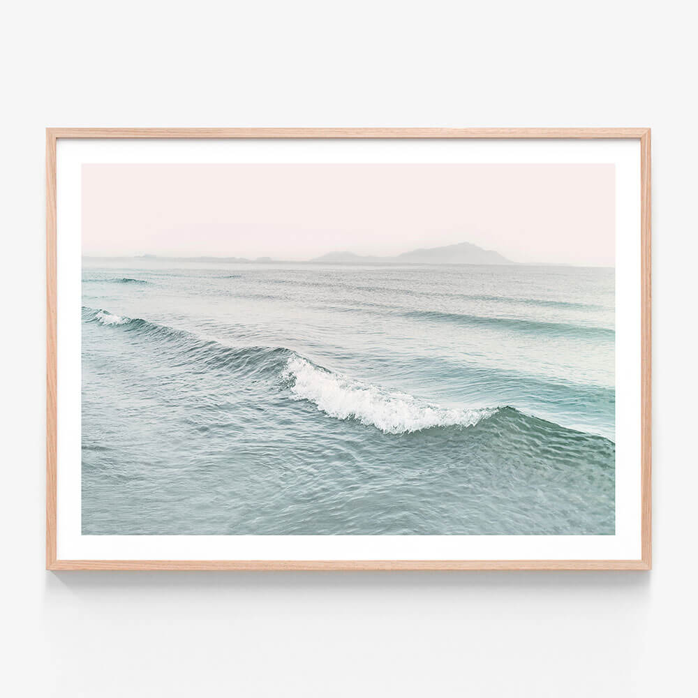 A framed photo wall art print featuring a coastal wave in pastel colours
